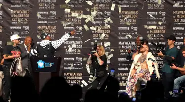 Petinju Floyd Mayweather melemparkan uang ke arah Conor McGregor saat konferensi pers tur dunia jelang pertandingannya di Barclays Center, Brooklyn, (13/7). Duel ini akan digelar di Las Vegas pada 26 Agustus. (Mike Lawrie/Getty Images/AFP)