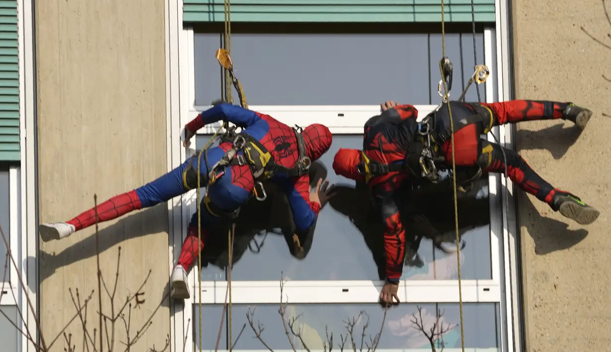 Dua orang berpakaian superhero turun dari atap untuk memberi kejutan di jendela kamar pasien anak di bangsal Pediatri rumah sakit San Paolo di Milan, Italia, Rabu (15/12/2021). Saat beraksi, para superhero memanjat dengan menggunakan tali dibekali alat pengaman yang lengkap. (AP Photo/Luca Bruno)