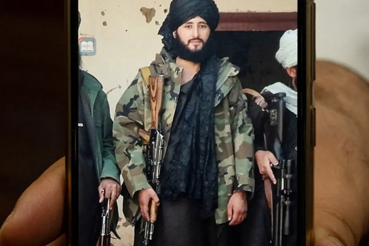 Foto yang diambil pada 18 Januari 2022 ini menunjukkan Wali Kota Maymana Damullah Mohibullah Mowaffaq memegang ponselnya dengan foto dirinya saat menjadi pejuang Taliban, di Maymana. (AFP)