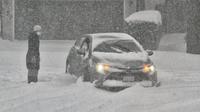 Wanita mencari cara untuk membebaskan mobil setelah terjebak di salju di jalan saat badai salju besar melanda Kanada, Toronto, dan Ontario. (The Guardian)