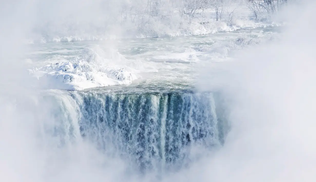 Es dan air mengalir di tepi Horseshoe Falls dari Air Terjun Niagara di Ontario, Kanada, Kamis (31/1). Cuaca dingin yang melanda Amerika Serikat (AS) membuat sebagian Air Terjun Niagara membeku. (Tara Walton/The Canadian Press via AP)