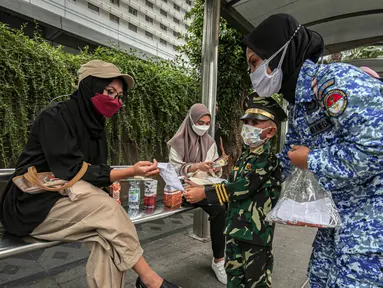 Perserta yang tergabung dalam Forum Kader Bela Negara DKI Jakarta membagikan bunga dan masker kepada warga di Jalan Thamrin, Jakarta, Rabu (22/12/2021). Aksi tersebut merupakan bentuk apresiasi terhadap kaum perempuan terutama pada peringatan Hari Ibu. (Liputan6.com/Faizal Fanani)