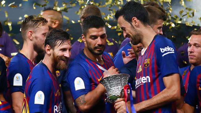 Pemain Barcelona Lionel Messi, Luis Suarez dan Sergio Busquets melihat Piala Super Spanyol usai pertandingan melawan Sevilla di Tangier, Maroko, (13/8). Barcelona berhasil mengalahkan Sevilla dengan skor 2-1. (AP Photo/Mosa'ab Elshamy)