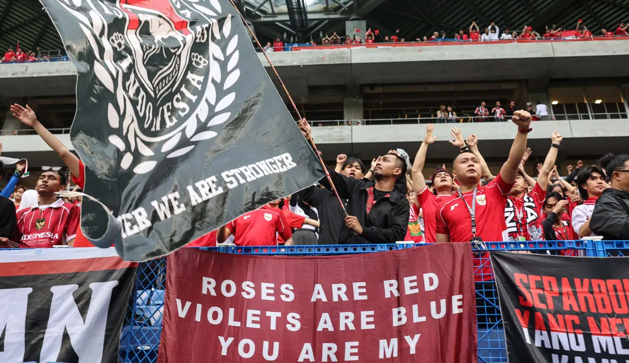Suporter tim Garuda melambaikan spanduk dan bersorak sebelum dimulainya pertandingan putaran ketiga kualifikasi Piala Dunia 2026 grup C antara Jepang dan Indonesia di Osaka pada 10 Juni 2025. (PAUL MILLER/AFP)