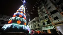 Pohon Natal berdiri di dekat bangunan yang hancur akibat serangan kelompok radikal di kawasan Al-Hamidiyah kota tua Homs, Suriah, (24/12). (REUTERS/Omar Sanadiki)