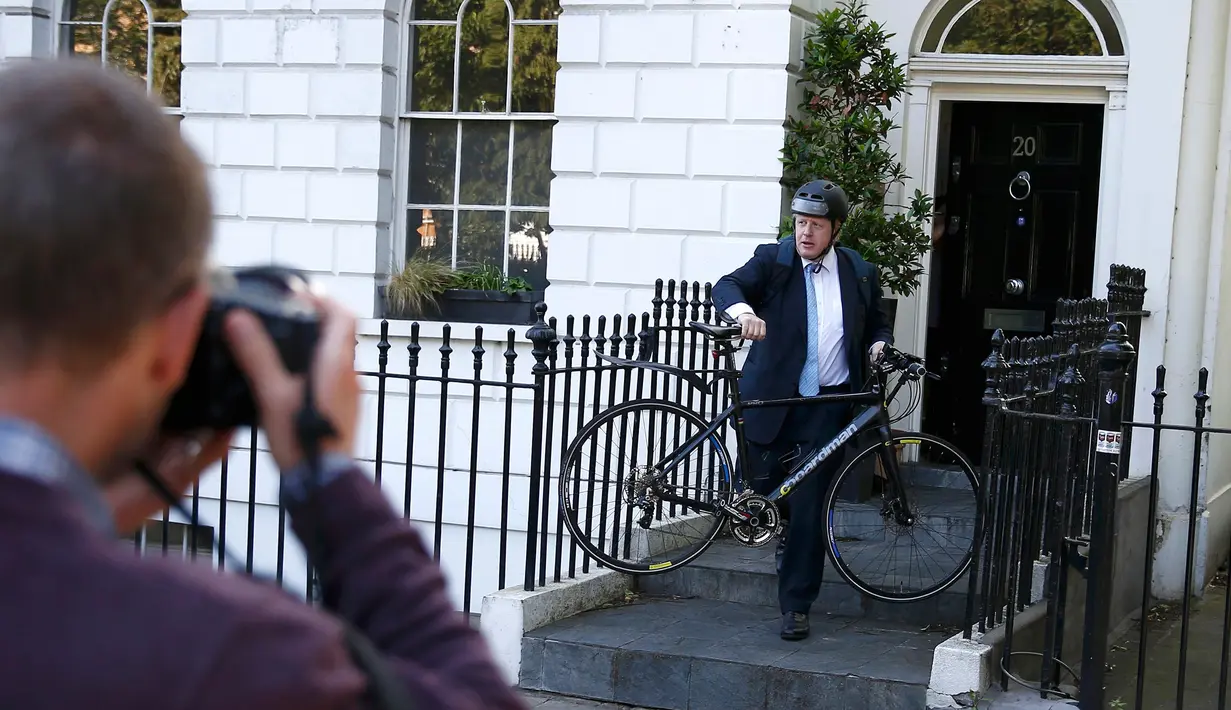 Seorang pria mengambil gambar Mantan Wali Kota London, Boris Johnson menggunakan sepeda saat akan meninggalkan rumahnya di London , Inggris, (21/6). (REUTERS / Peter Nicholls)