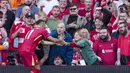 Pemain Liverpool, Mohamed Salah mengambil gawai dari salah satu suporter timnya untuk berswafoto setelah mencetak gol ke gawang Tottenham Hotspur dalam laga lanjutan Liga Inggris 2024/2025 di Anfiled, Liverpool, Inggris, Minggu (27/04/2025) waktu setempat. (AP Photo/Jon Super)