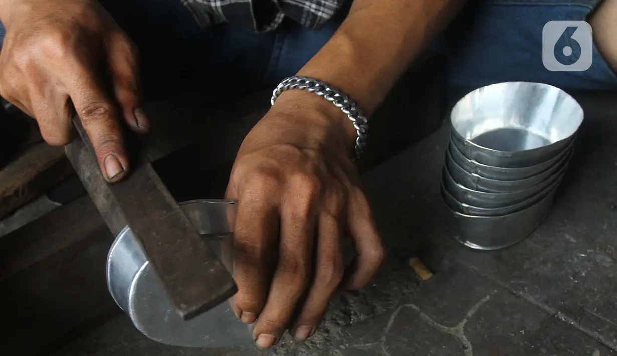 Seorang pengrajin membuat tempat cuci tangan di Pamulang, Tangerang Selatan, Banten  Minggu( 12/1/2020). Perabot tersebut dibuat dari bahan aluminium seperti dandang, oven, panci dan ventilator dijual dengan harga 100 sampai 300 ribu rupiah tergantung besar kecilnya. (merdeka.com/Arie Basuki)