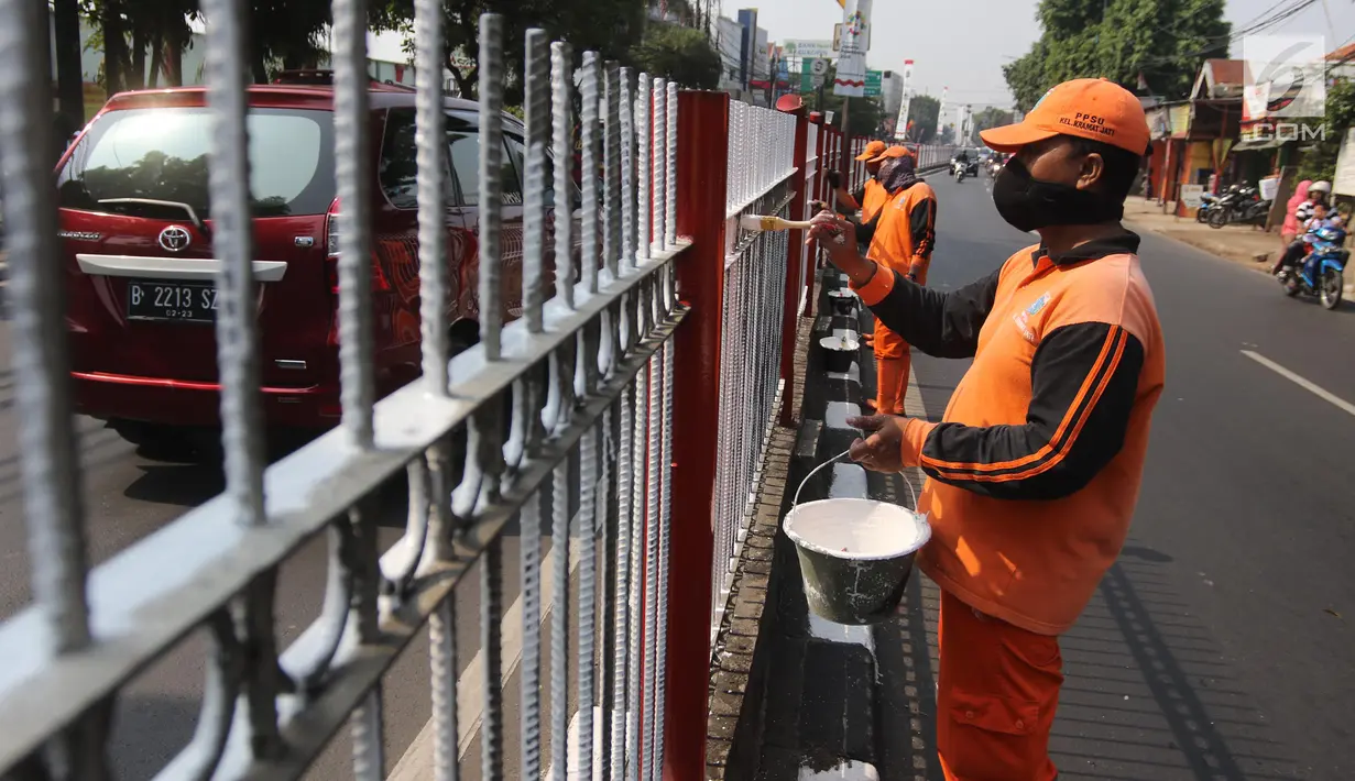Petugas PPSU Kelurahan Kramat Jati mengecat ulang pagar pembatas Jalan Raya Bogor, Jakarta, Selasa (17/7). Pengecatan sebagai upaya perawatan berkala terhadap sarana dan prasarana yang sudah mulai kehilangan fungsi atau rusak. (Liputan6.com/Arya Manggala)