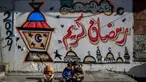 Anak-anak Palestina duduk di depan tembok dengan gambar bertema Ramadan di Kota Gaza pada 8 Maret 2024. (Foto: AFP)