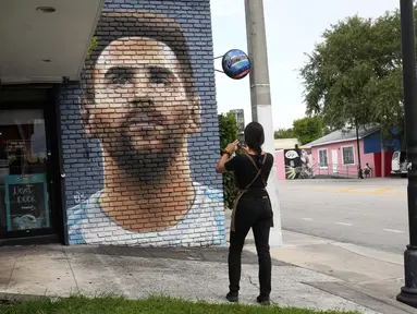 Jessica Ospina mengambil foto mural Lionel Messi di luar restoran Fiorito, di Miami, Amerika Serikat, Rabu, 7 Juni 2023. (AP Photo/Lynne Sladky)