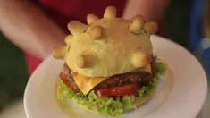 Pemilik restoran Hoang Tung menunjukkan burger berbentuk virus corona COVID-19 di Hanoi, Vietnam, Rabu (25/3/2020). Sebuah restoran di Hanoi membuat kreasi baru mereka yang disebut ‘Burger Corona’. (AP Photo/Hau Dinh)
