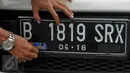 Pengendara mencopot stiker Mabes AL di plat mobil yang dikendarainya saat Operasi Gaktib Garnisun Tetap 1 di kawasan Pesing, Jakarta,  Kamis, (11/2/2016). (Liputan6.com/Faisal R Syam)