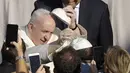 Paus Fransiskus menukar topi yang disumbangkan oleh umat saat ia tiba di halaman St. Damaso pada kesempatan audiensi umum mingguan di Vatikan, Rabu (16/9/2020). (AP Photo/Gregorio Borgia)