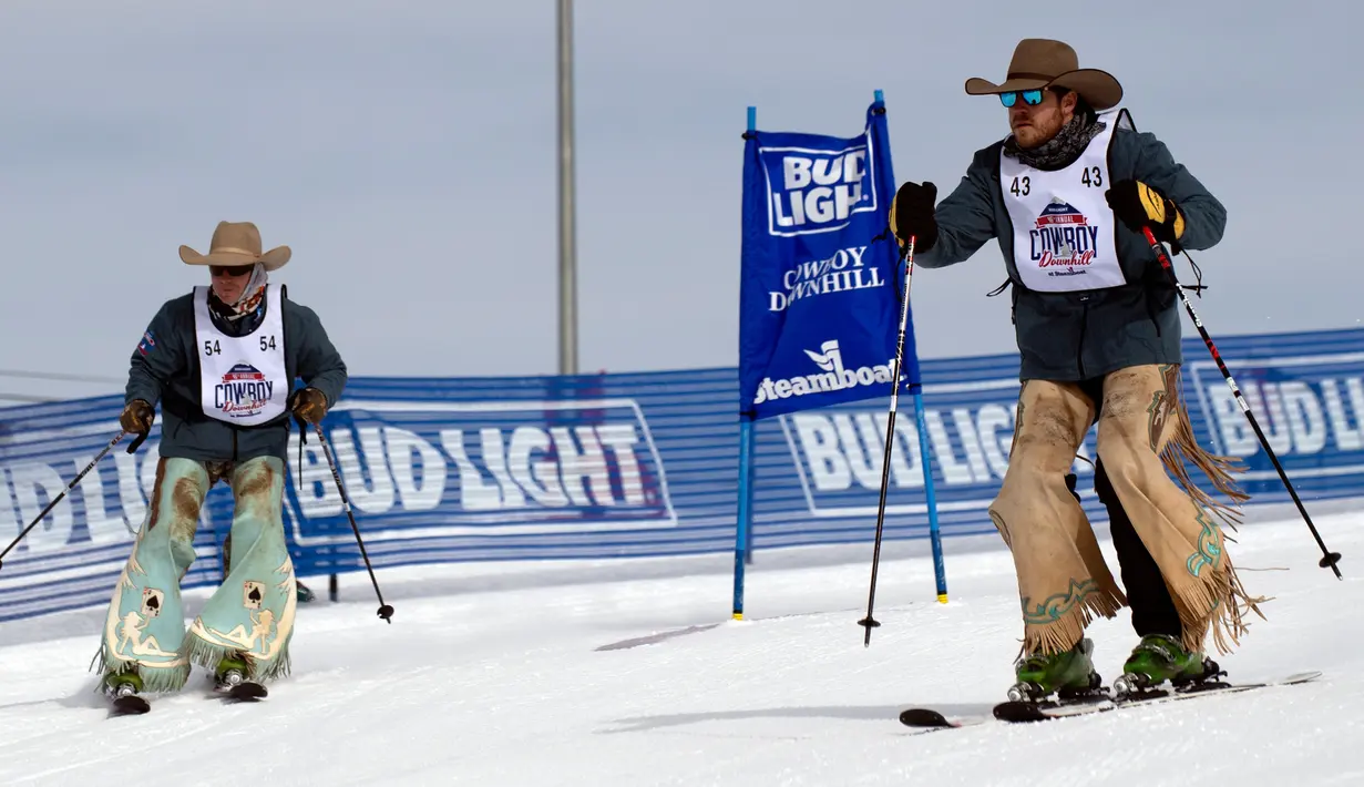 Koboi rodeo, Landon Mecham (kiri) dan Justin Lawrence bersaing selama turnamen Cowboy Downhill ke-46 di Steamboat Springs, Colorado, 20 Januari 2020. Para koboi yang biasa menunggangi kuda atau banteng ini ditantang untuk meluncur menggunakan papan ski dan snowboard. (Jason Connolly/AFP)