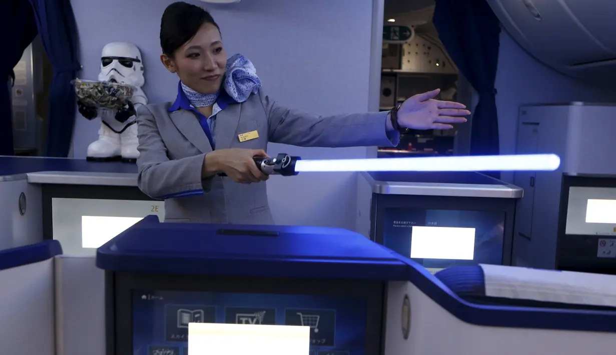 Seorang Pramugari menyapa pengunjung sambil memegang lightsabre atau pedang laser di pesawat Boeing 787 Dreamliner, Singapura, Kamis (12/11/2015).  Pesawat bertema Star Wars ini menjadi pertama di Asia Tenggara. (REUTERS/Edgar Su)