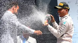 Pembalap Formula 1, Lewis Hamilton menyemprotkan sampanye usai menjuarai Grand Prix Formula 1 Silverstone di Inggris, (5/7/2015). Hamilton berhasil finish di urutan pertama dengan waktu 1 jam 31 menit 27,729 detik. (Reuters/Paul Childs)
