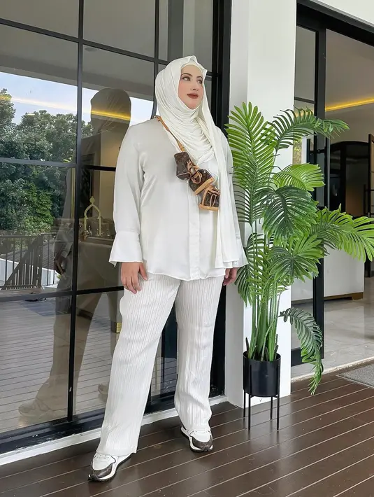Ia mengenakan kemeja lengan panjang satin, dipadunya dengan celana panjang, serta hijab yang juga berwarna putih polos. [Foto: Instagram/tasyiiathasyia]