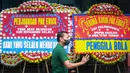 Seorang petugas melewati karangan bunga yang membanjiri kantor PSSI di GBK Arena, Senayan, Jakarta, Kamis (30/03/2023) sebagai respon pembatalan Indonesia sebagai tuan rumah Piala Dunia U-20 2023 oleh FIFA. (Bola.com/Bagaskara Lazuardi)
