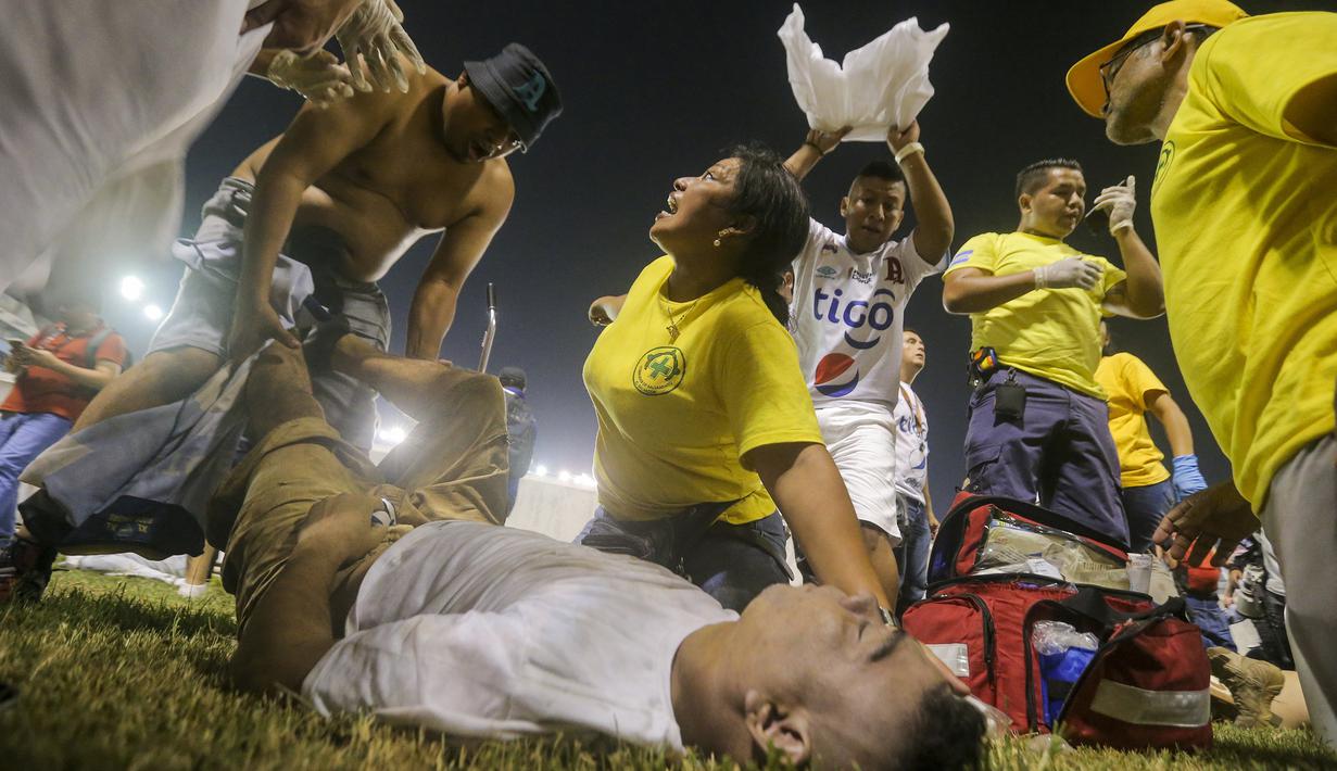 Tim medis dan beberapa sukarelawan tampak memberikan pertolongan kepada seorang korban saat terjadi kerusuhan suporter akibat saling berebut masuk ke dalam Stadion Monumental, Cuscatlan, San Salvador, El Salvador, Sabtu (21/5/2023) waktu setempat untuk menyaksikan laga perempatfinal Divisi Utama El Salvador antara Alianza FC menghadapi Deportivo FAS. (AP Photo/Milton Flores)