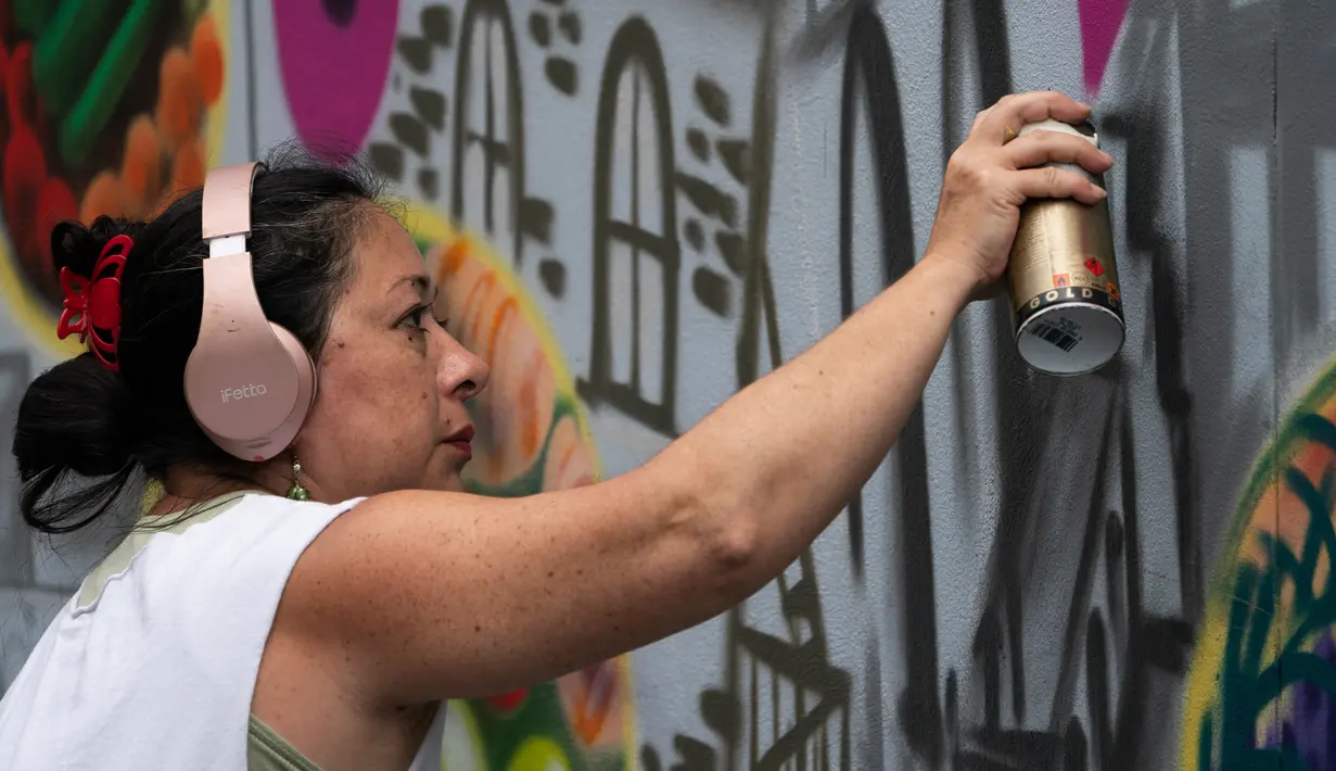 Seniman grafiti Sandra Fabara atau lebih dikenal Lady Pink melukis mural di Casita Maria, Bronx, New York, AS, Minggu (2/6/2019). Kesukaan Lady Pink terhadap dunia grafiti berawal saat dirinya melukis subway New York pada tahun 1979. (Don Emmert/AFP)