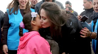 Utusan khusus lembaga pengungsi PBB, aktris Angelina Jolie mendapat ciuman seorang anak Suriah saat berkunjung ke Kamp Pengungsi Zaatari di Mafraq, Yordania, Minggu (28/1). Jolie mengaku prihatin dengan kondisi pengungsi Suriah. (AP Photo/Raad Adayleh)