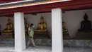 Turis yang mengenakan masker berjalan-jalan di kuil Wat Pho di Bangkok, Thailand, pada 23 Februari 2022. Thailand akan melonggarkan beberapa persyaratan masuk bagi turis asing untuk membangun kembali yang rusak akibat pandemi ekonomi mulai 1 Maret mendatang. (AP Photo/Sakchai Lalit)