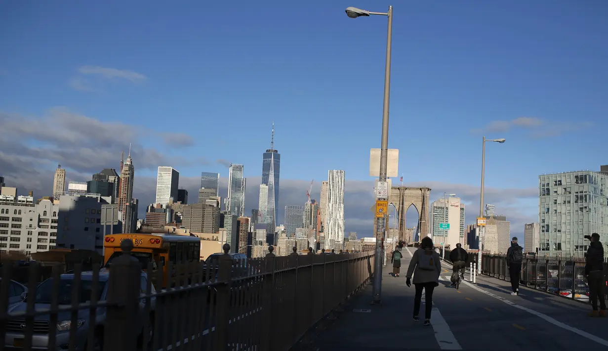 Orang-orang melintasi Jembatan Brooklyn dengan latar belakang kota Manhattan di New York, 4 Desember 2018. Jembatan karya insyinur John Augustus Roebling ini menghubungkan borough Manhattan dan Brooklyn melintasi Sungai East. (AP /Wong Maye-E)