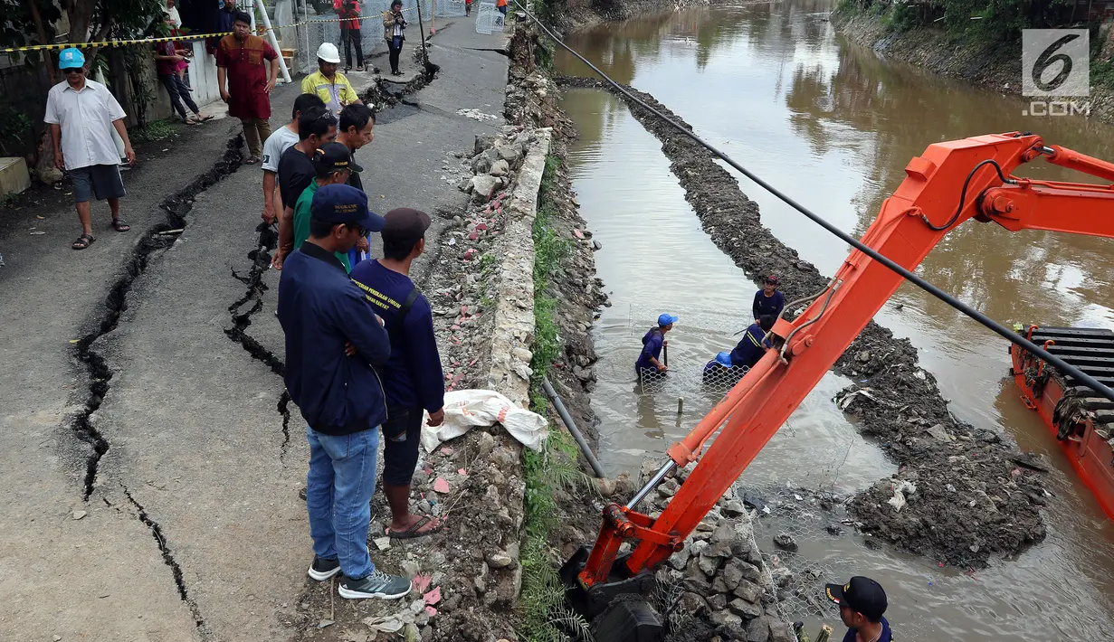 Petugas memasang beronjong kawat di bagian bawah jalan yang retak di Kelurahan Kebon Manggis, Kecamatan Matraman, Jakarta Timur, Jumat (16/2). Satu unit ekskavator juga dikerahkan di Sungai Ciliwung di samping jalan yang retak. (Liputan6.com/Johan Tallo)