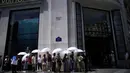 Orang-orang menggunakan payung untuk melindungi diri dari sinar matahari saat mereka mengantre untuk memasuki toko Louis Vuiton di jalan Champs Elysee, di Paris, Prancis, Rabu (18/5/2022). Cuaca panas diperkirakan akan berlangsung selama beberapa hari di seluruh Prancis. (AP Photo/Christophe Ena)