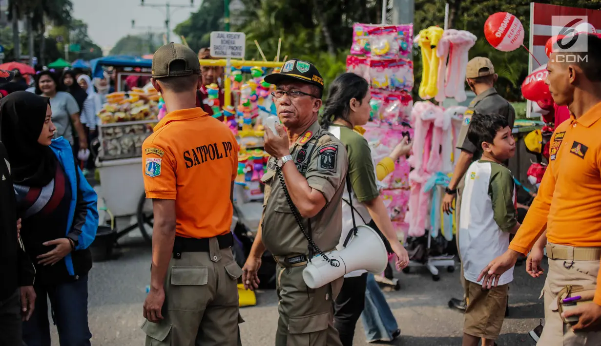 Petugas Satpol PP melakukan sosialisasi saat menertibkan PKL di kawasan car free day (CFD), Bundaran HI, Jakarta, Minggu (4/8/2019). Penertiban dilakukan karena keberadaan PKL membuat tidak nyaman pengunjung CFD yang ingin berolahraga, berorasi, atau sekadar jalan-jalan. (Liputan6.com/Faizal Fanani)