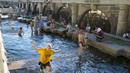 Anak-anak menyejukkan diri di air Sungai Neglinnaya saat menikmati penghujung hari yang panas di dekat Tembok Kremlin, Moskow, Rusia, 3 Juli 2022. Cuaca panas di Moskow datang dengan perkiraan suhu mencapai 30 derajat Celcius (86 Fahrenheit). (AP Photo/Alexander Zemlianichenko)