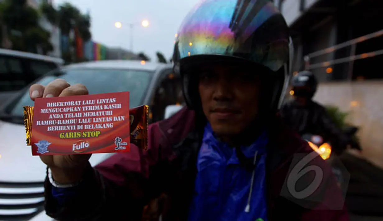Seorang pengendara roda dua mendapatkan bingkisan coklat fullo sebagai apresiasi disiplin berlalu lintas di kawasan perempatan Cideng, Jakarta, Senin (23/2). (Liputan6.com/Johan Tallo)