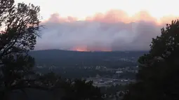Kebakaran hutan yang membakar memancarkan cahaya di atas lingkungan di pinggiran Flagstaff, Arizona, Minggu (12/6/2022). Evakuasi telah diperintahkan untuk rumah-rumah di daerah tersebut. Pihak berwenang mengatakan petugas pemadam kebakaran menanggapi kebakaran hutan sekitar enam mil di utara Flagstaff yang telah memaksa evakuasi. (AP Photo/Felicia Fonseca)