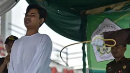 Ekspresi seorang pria saat menjalani hukuman cambuk setelah ketahuan melakukan hubungan seks pranikah di sebuah stadion di Lhokseumawe di provinsi Aceh (31/7/2019). Dua pria dan seorang wanita dicambuk secara terbuka sebanyak 100 kali karena melanggar hukum Islam di daerah tersebut. (AFP Photo/Rahma