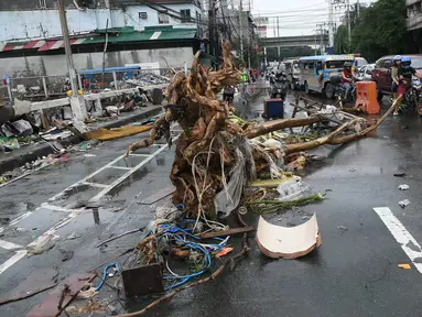 Pengendara kendaraan bermotor melewati batang pohon yang tergeletak di salah satu jalan di Manila, Filipina pada 25 Juli 2024. (TED ALJIBE/AFP)