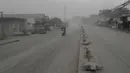Pengendara sepeda motor melintasi jalan yang tertutup abu vulkanik dari gunung berapi Taal di Lemery, provinsi Batangas, Filipina, Senin (13/11/2020). Erupsi gunung Taal memaksa puluhan ribu orang mengungsi serta membuat sekolah-sekolah dan toko di Manila tutup. (AP/Aaron Favila)