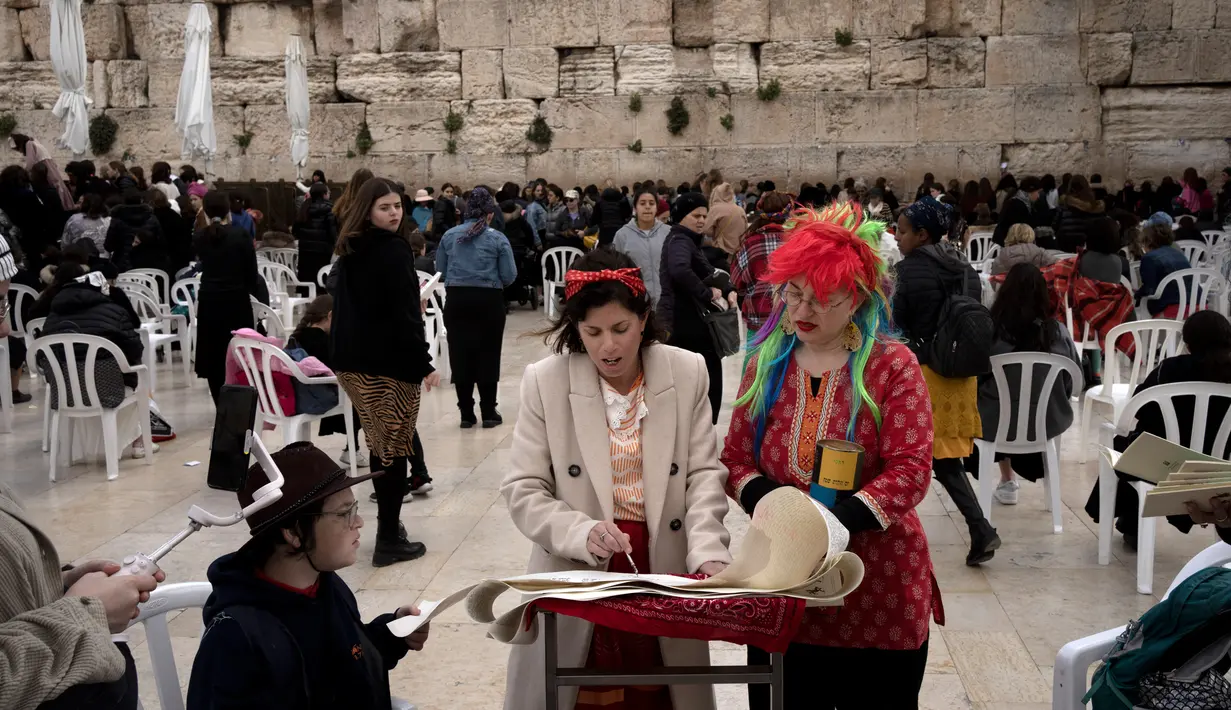 Kepemimpinan Wanita Tembok Yochi Rappeport (tengah) dan Rachel Cohen Yeshurun (kanan) membaca Kitab Ester selama Hari Raya Purim yang tahun ini bertepatan dengan Hari Perempuan Internasional di bagian wanita di Tembok Barat, Kota Tua Yerusalem, 8 Maret 2023. Kelompok ini telah melakukan perjuangan selama puluhan tahun untuk kesetaraan gender di tempat tersuci orang Yahudi dapat berdoa tersebut. (AP Photo/Maya Alleruzzo)