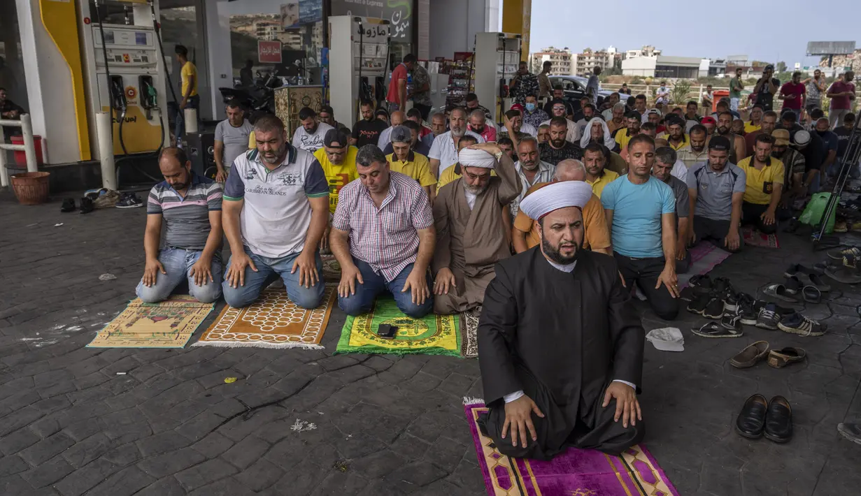 Umat Muslim melaksanakan salat Jumat di sebuah pompa bensin di kota pesisir Jiyeh, selatan Beirut, Lebanon, Jumat (3/9/2021). Puluhan jemaah berlutut dalam salat Jumat di tengah ratusan mobil dan pengendara yang antre untuk mengisi mobilnya dengan bahan bakar. (AP Photo/ Hassan Ammar)