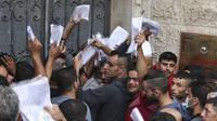Kerumunan pria Palestina memegang dokumen identitas untuk mengajukan izin kerja di Israel, di kamp pengungsi Jabalia di Jalur Gaza utara, Rabu (6/10/2021). Israel telah membuka kembali gerbangnya bagi para pekerja dari kantong Palestina itu setelah perang terbaru pada Mei lalu. (MAHMUD HAMS / AFP)