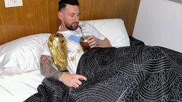 Kapten dan penyerang Argentina Lionel Messi menikmati minuman sambil memeluk trofi Piala Dunia 2022 di tempat tidur di pusat pelatihan AFA di Ezeiza, Buenos Aires, Argentina pada 20 Desember 2022. Trofi Piala Dunia merupakan satu-satunya gelar yang belum pernah diangkat pemain 35 tahun itu. Impiannya kini menjadi nyata trofi itu dipeluk sambil tidur. (Instagram/leomessi)