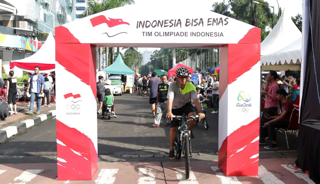 Warga melintas deket gapura kampanye Indonesia Bisa Emas, Road to Rio 2016 di Senayan, Jakarta, Minggu (20/3/2016). (Bola.com/Nicklas Hanoatubun)