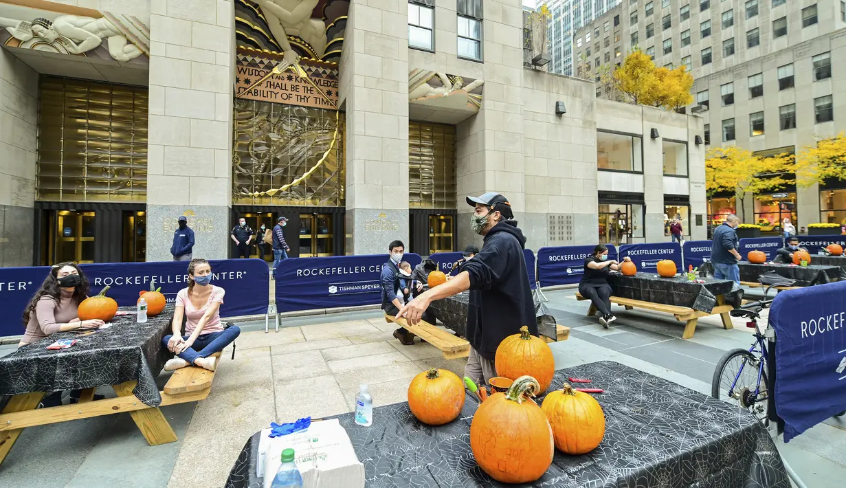 Chris Soria, dari Maniac Pumpkin Carvers di Brooklyn, mengajari orang-orang yang bekerja di Rockefeller Center cara mengukir lentera jack o 'untuk Halloween (22/10/2020). (Diane Bondareff/AP Images for Tishman Speyer)