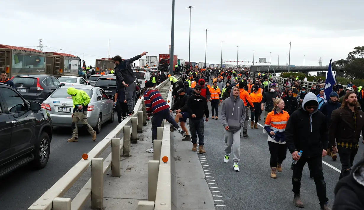 Pekerja konstruksi dan demonstran menghadiri protes terhadap peraturan Covid-19 di Melbourne (21/9/2021). Ribuan orang membuat kekacauan dan bentrok dengan polisi di kota dan mengambil alih jalan raya utama Melbourne saat protes terjadi. (AFP/Con Chronis)