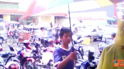 Citizen6, Tasikmalaya: Seorang anak sedang berusaha menawarkan payung untuk digunakan pejalan kaki.