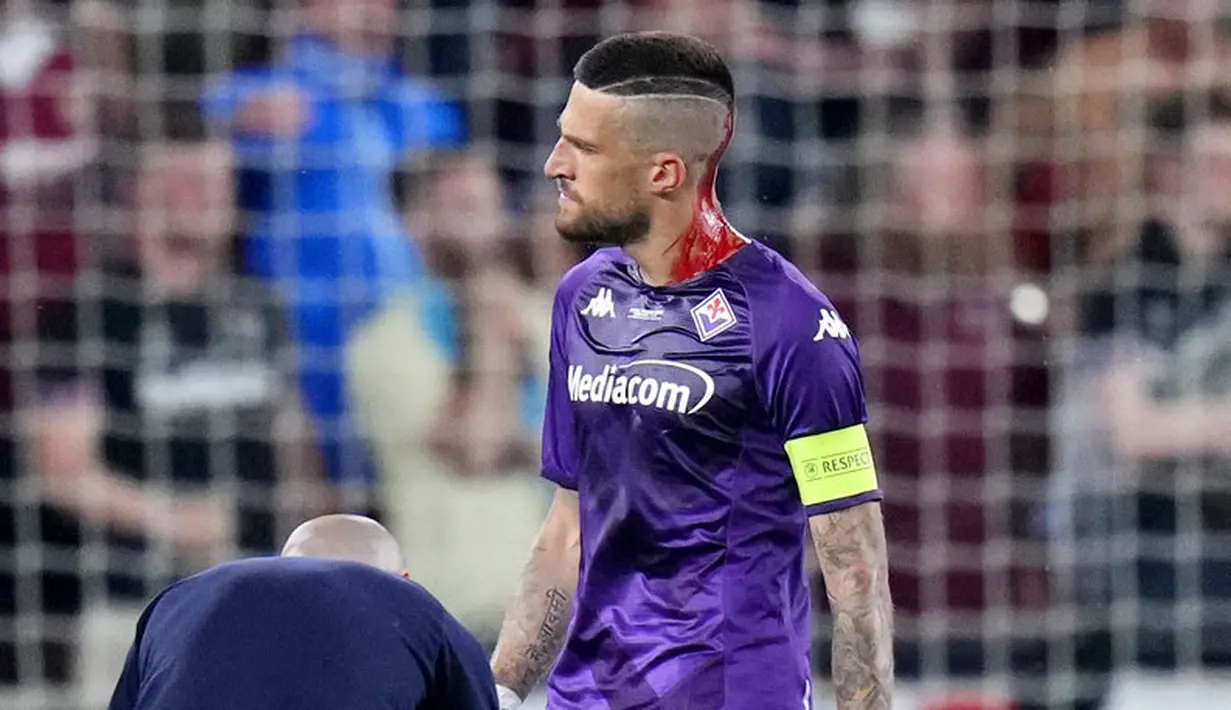 Darah mengalir di kepala pemain Fiorentina, Cristiano Biraghi, setelah insiden pelemparan benda dari tribun suporter West Ham United pada laga final UEFA Europa Conference League di Stadion Eden Arena, Kamis (8/6/2023). Fiorentina takluk dengan skor 1-2. (AP Photo/Petr David Josek)