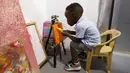 Ace-Liam Nana Sam Ankrah, yang akan berulang tahun ke dua pada bulan Juli, memamerkan tabung catnya di galeri seni ibunya di Accra, Ghana, pada 27 Mei 2024. (AP Photo/Misper Apawu)