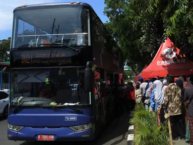 Antrean warga menaiki bus tingkat untuk wisata keliling Ibu Kota di depan Masjid Istiqlal, Jakarta, Sabtu (31/3). Libur tiga hari di penghujung Maret 2018 dimanfaatkan untuk berkeliling Jakarta menggunakan bus tingkat City Tour. (Merdeka.com/Imam Buhori)
