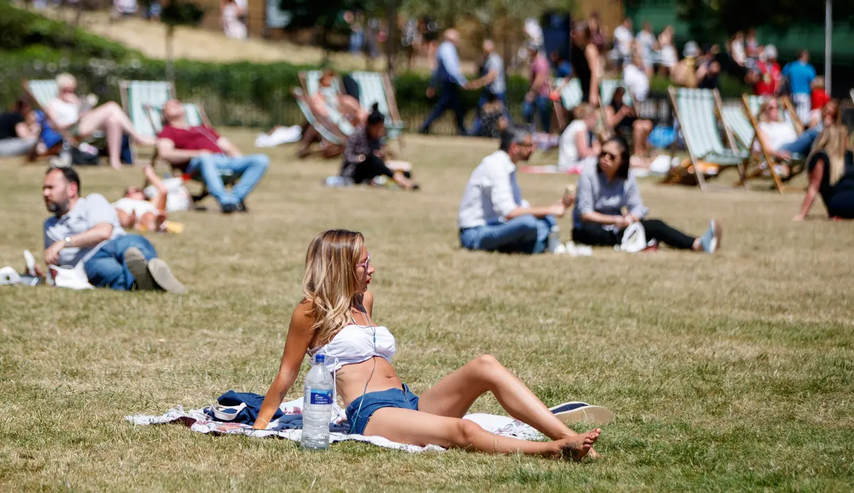 Sejumlah warga Inggris bersantai di atas rumput sambil menikmati sinar matahari di Green Park, London, Senin (25/6). Pada Juli 2018, suhu di ibu kota London tercatat 29.1 derajat Celcius dan diprediksi akan mencapai 30 derajat Celcius. (AFP/Tolga Akmen)