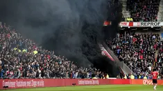 Asap hitam menyelimuti tribun penonton saat pertandingan sepak bola PSV Eindhoven vs Ajax dalam pertandingan Liga Eredivisie di Stadion Philips, Belanda (23/4). Asap hitam tebal tersebut sempat mengganggu jalannya pertandingan. (Olaf KRAAK / ANP / AFP)
